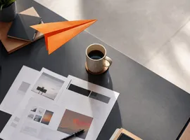 Avión de papel despegando sobre bocetos de una web nueva, simbolizando el impulso de una campaña de ads