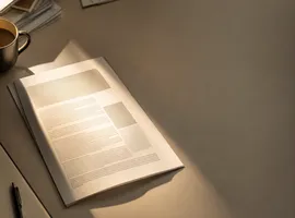 Documento de un artículo iluminado por un foco de luz, representando el impulso de amplificar contenido con publicidad
