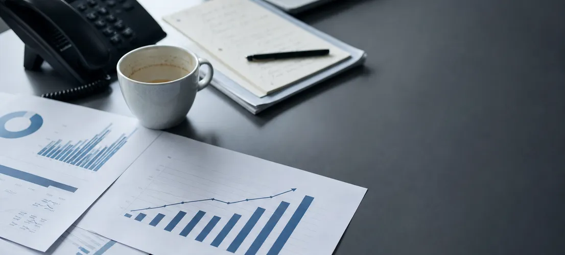 Escritorio con informes de tráfico SEO y teléfono en silencio, símbolo de agencia SEO sin generar negocio real