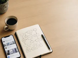 Escritorio con móvil y libreta mostrando el contraste entre publicar en redes y tener un sistema de contenido