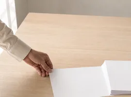 Mano impulsando una hoja de papel entre otras quietas, representando la distribución de contenido de un blog