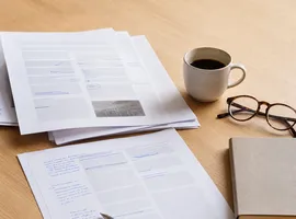 Documentos de contenido revisados a mano sobre un escritorio, representando el ajuste de la voz de marca en servicios profesionales